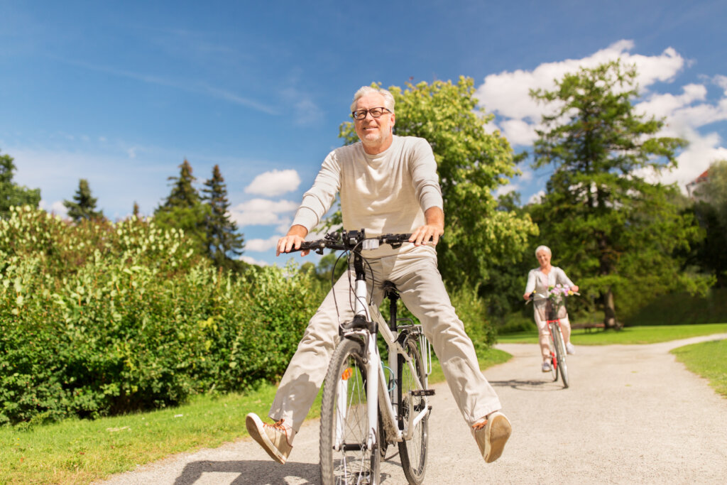 active old age, people and lifestyle concept - happy senior couple riding bicycles at summer park