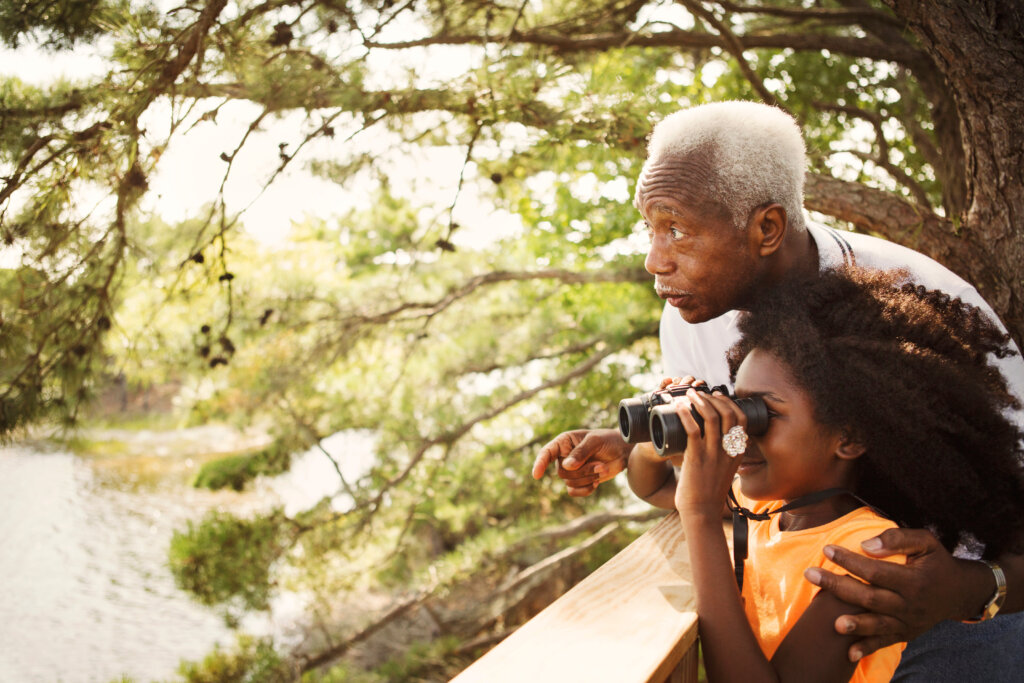 grandpa and granddaughter looking at nature through binoculars