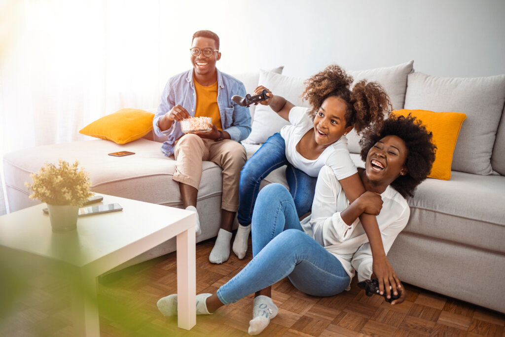 happy family at home sitting in sofa couch and playing console video games together