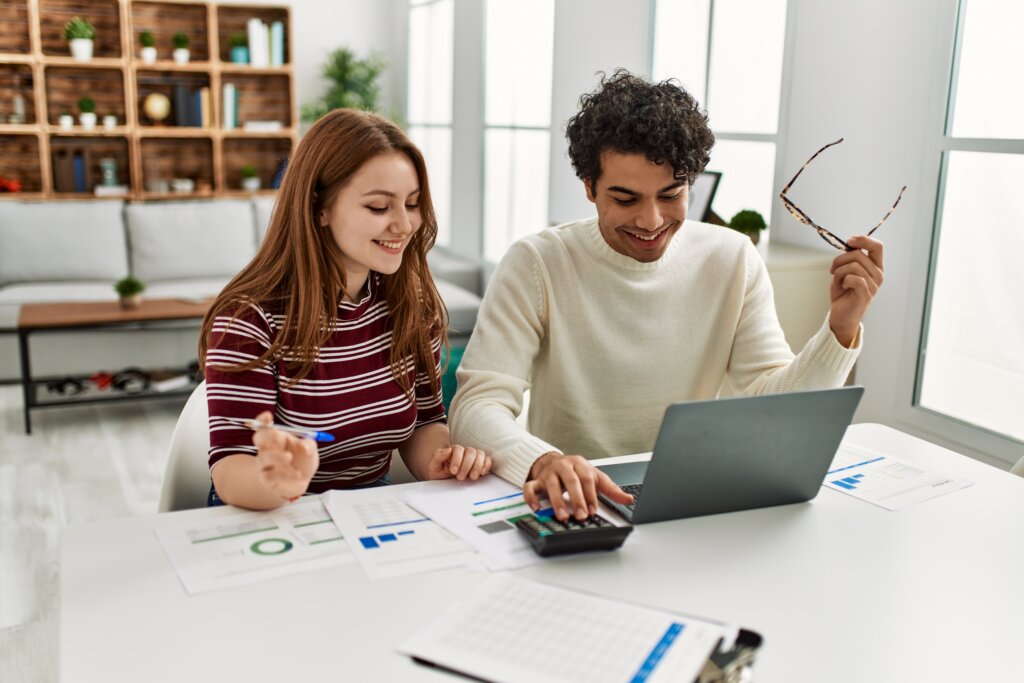 Young couple smiling happy using laptop sitting on the table at home.