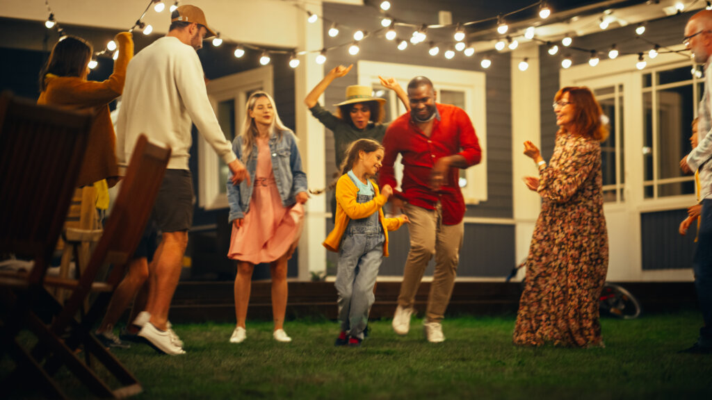 Friends and Family Dancing Together at an Outdoors Evening Garden Party Celebration. 