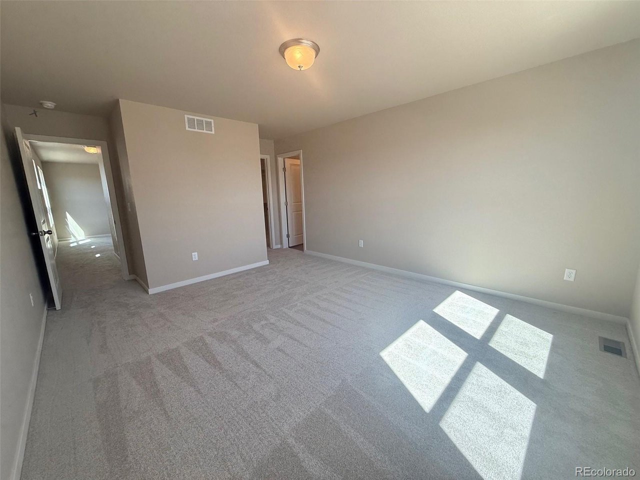 bedroom with beige walls, ceiling light, carpeted floor, and doorway leading to a hallway and closet