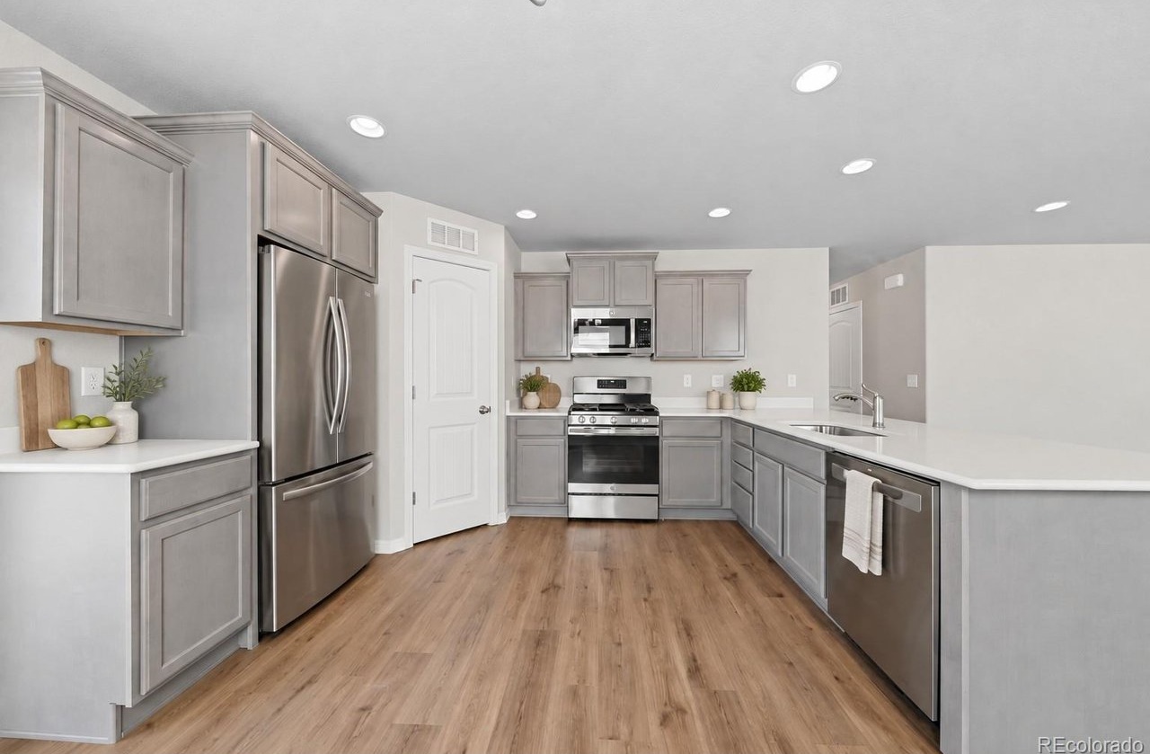 kitchen with gray cabinetry, stainless steel appliances, island with sink, and recessed ceiling lights